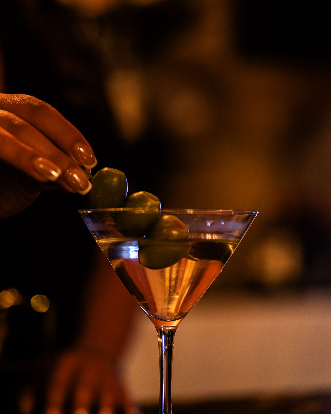 Bartender garnishing a martini with olives