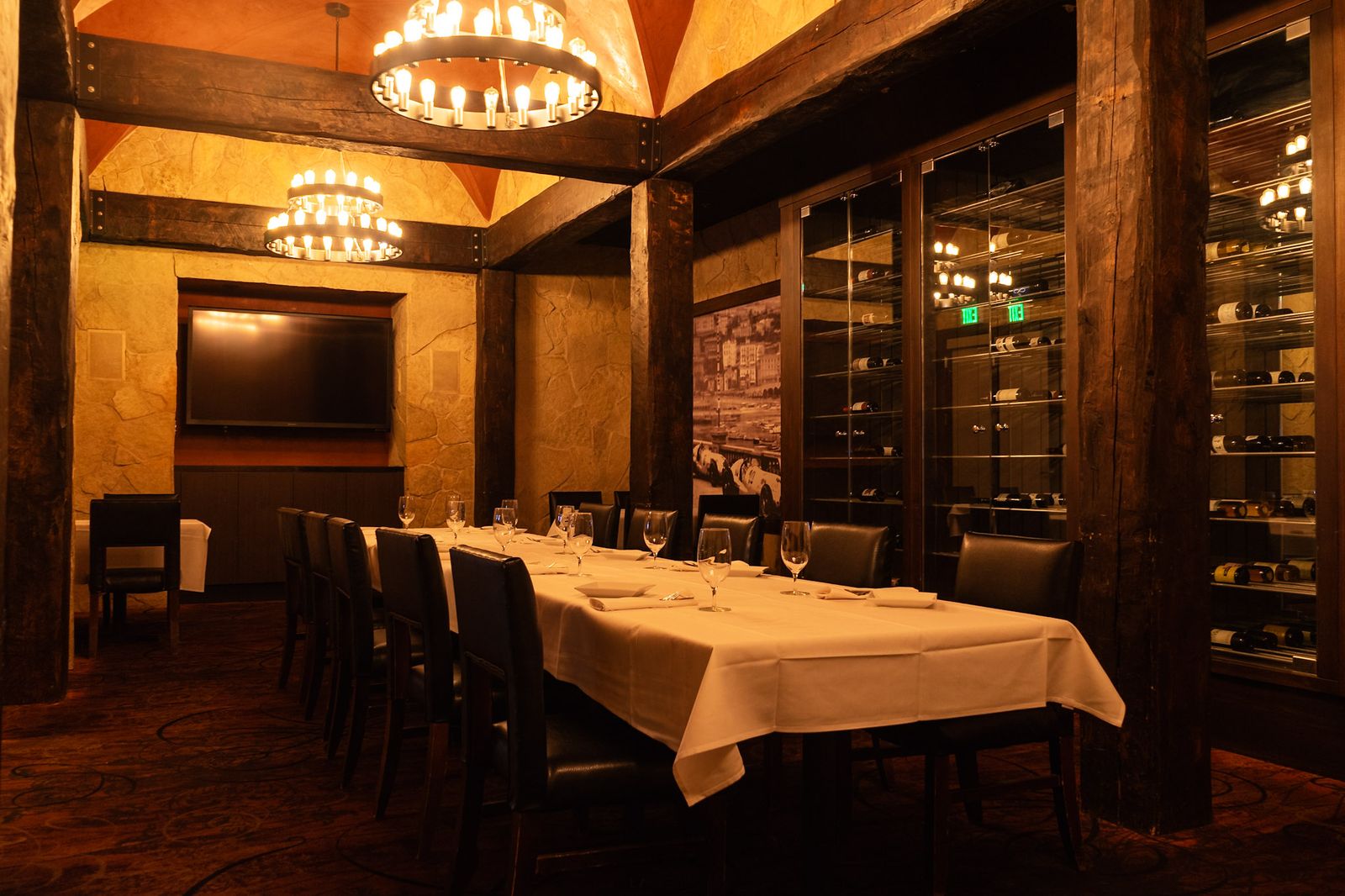 Long private dining table set for a group beside the glass wine cellar